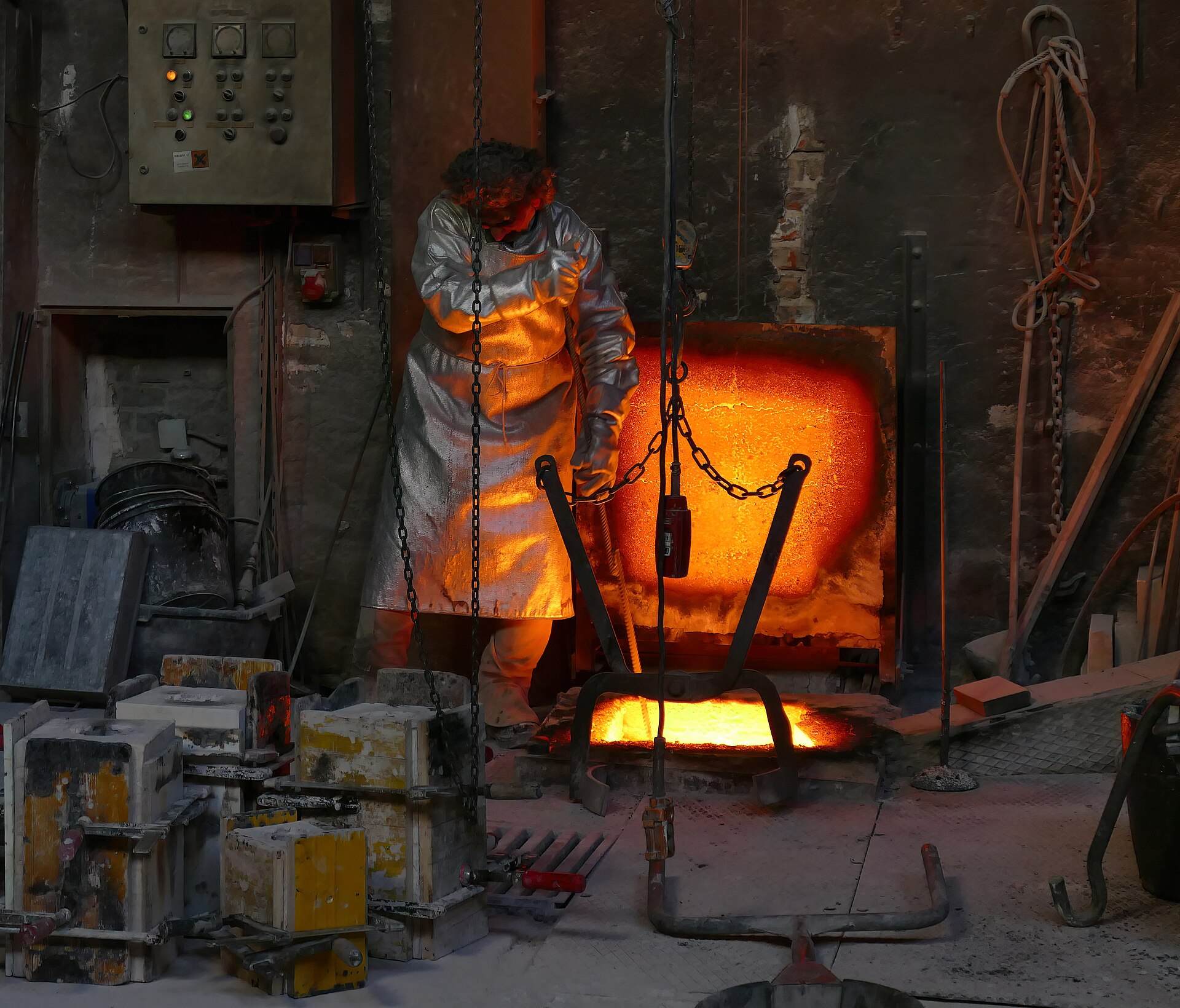 A foundry worker monitors molten metal being poured into a mold, illustrating the intense process of creation like casting a.