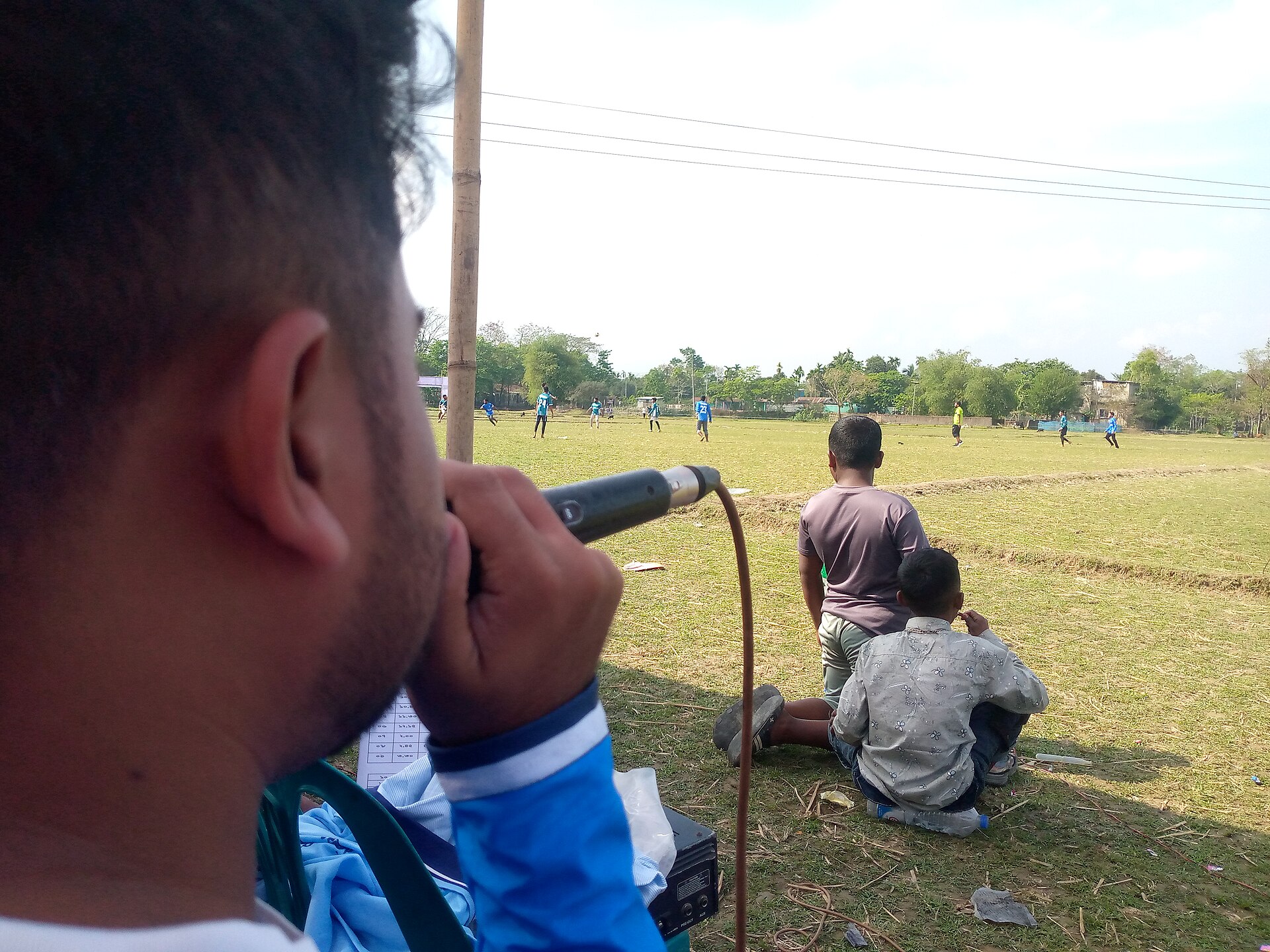 A sports commentator describes a soccer game as spectators watch, reflecting the social life of television and fan culture.